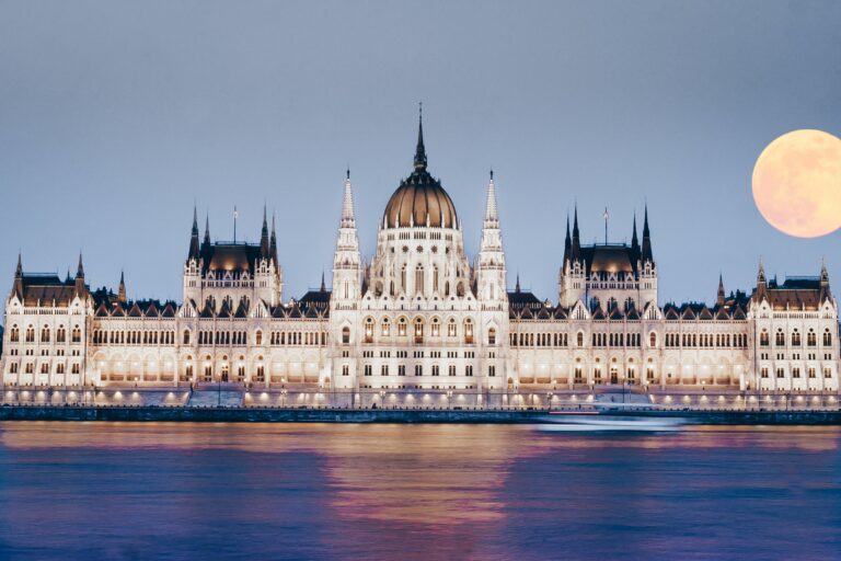 Majestátní bílý palác s tmavou střechou stojící před jezerem